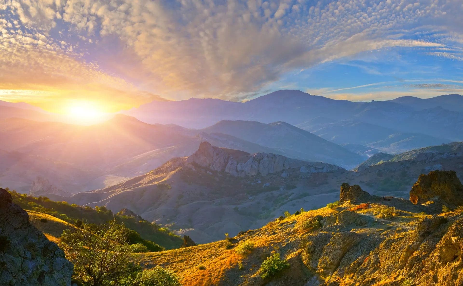 Sunrise breaking over layered mountain ridges